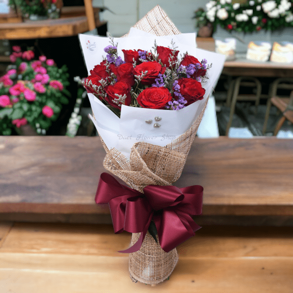 Bouquet of 12 red roses in white paper and burlap.