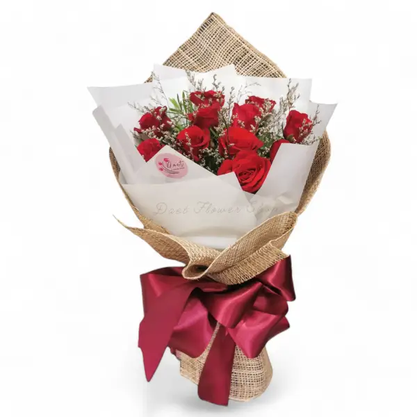 Bouquet of dozen red roses in white wrap and burlap with maroon ribbon.