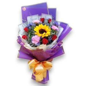 Bouquet of sunflower, roses, carnations in purple wrap